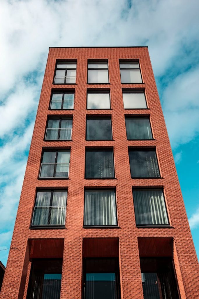 Red-brick modern building against a vibrant blue sky and clouds.