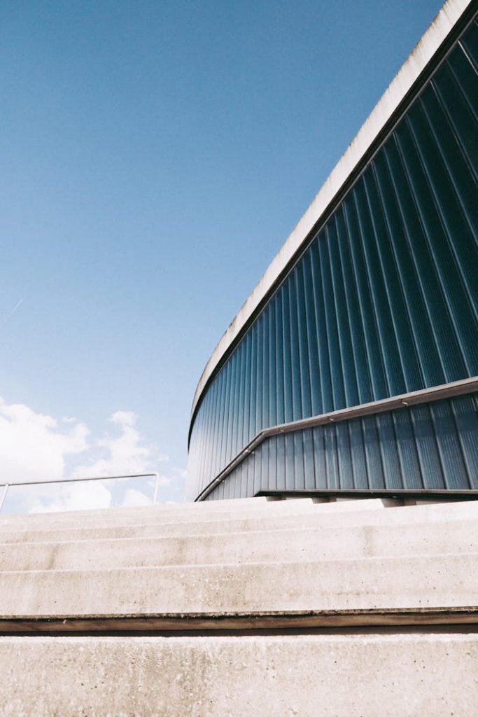 Low angle view of a modern blue facade building with clear sky, showcasing sleek architecture.