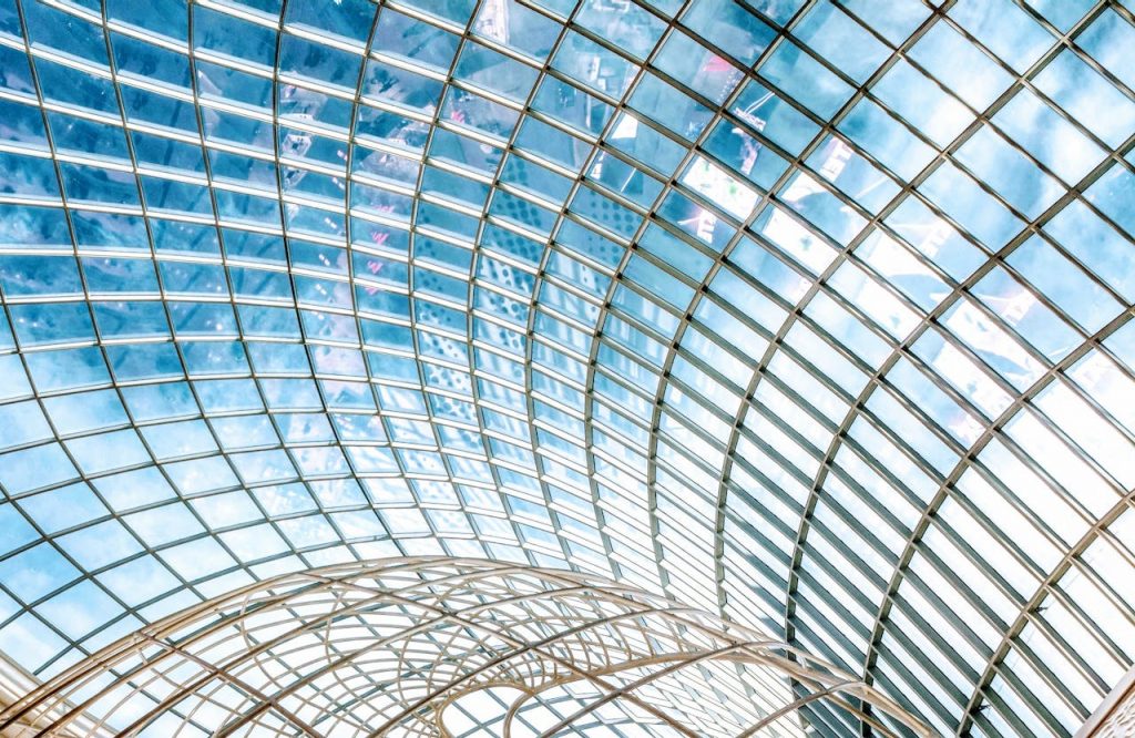 Captivating view of a futuristic glass roof with geometric patterns and sky reflection.