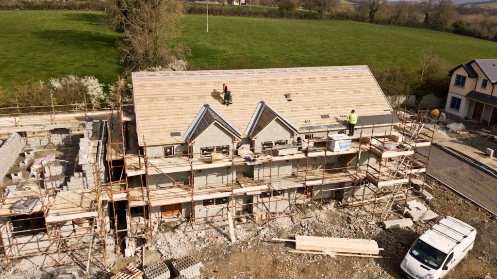 Aerial shot of a house under construction in Clonmel, Ireland. Workers on the roof.